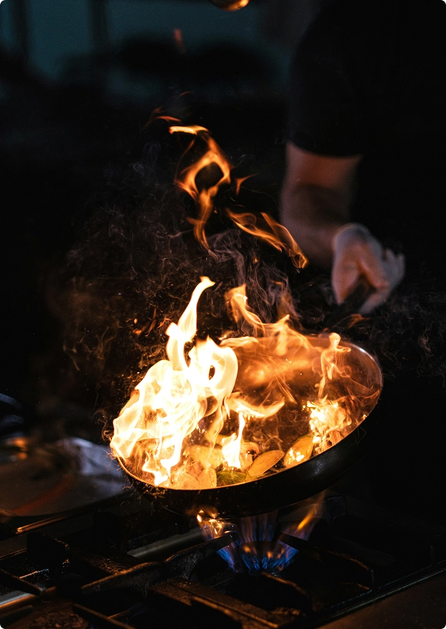 Chef cooking in a flaming wok in an open kitchen